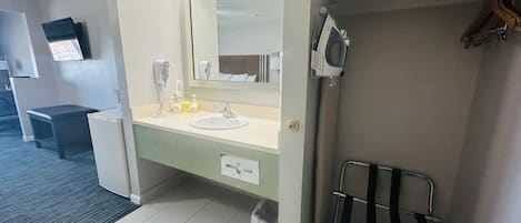 A hotel bathroom with a sink, mirror, hairdryer, and towel rack.