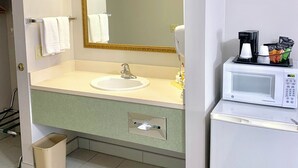 A bathroom with a sink, mirror, and a microwave.