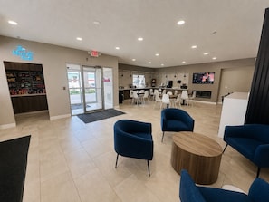 A modern interior with a reception area, seating, and a kitchen visible through the glass doors. - BridgePointe Inn & Suites by BPhotels, Lincoln I-80/27th St (Lincoln)