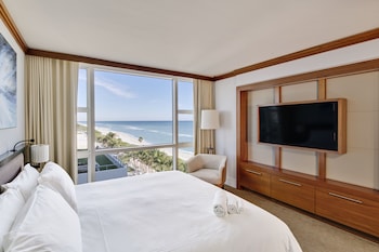 A beach with sun loungers and umbrellas, a clear blue sky, and the ocean in the background. at Carillon Miami Wellness Resort
