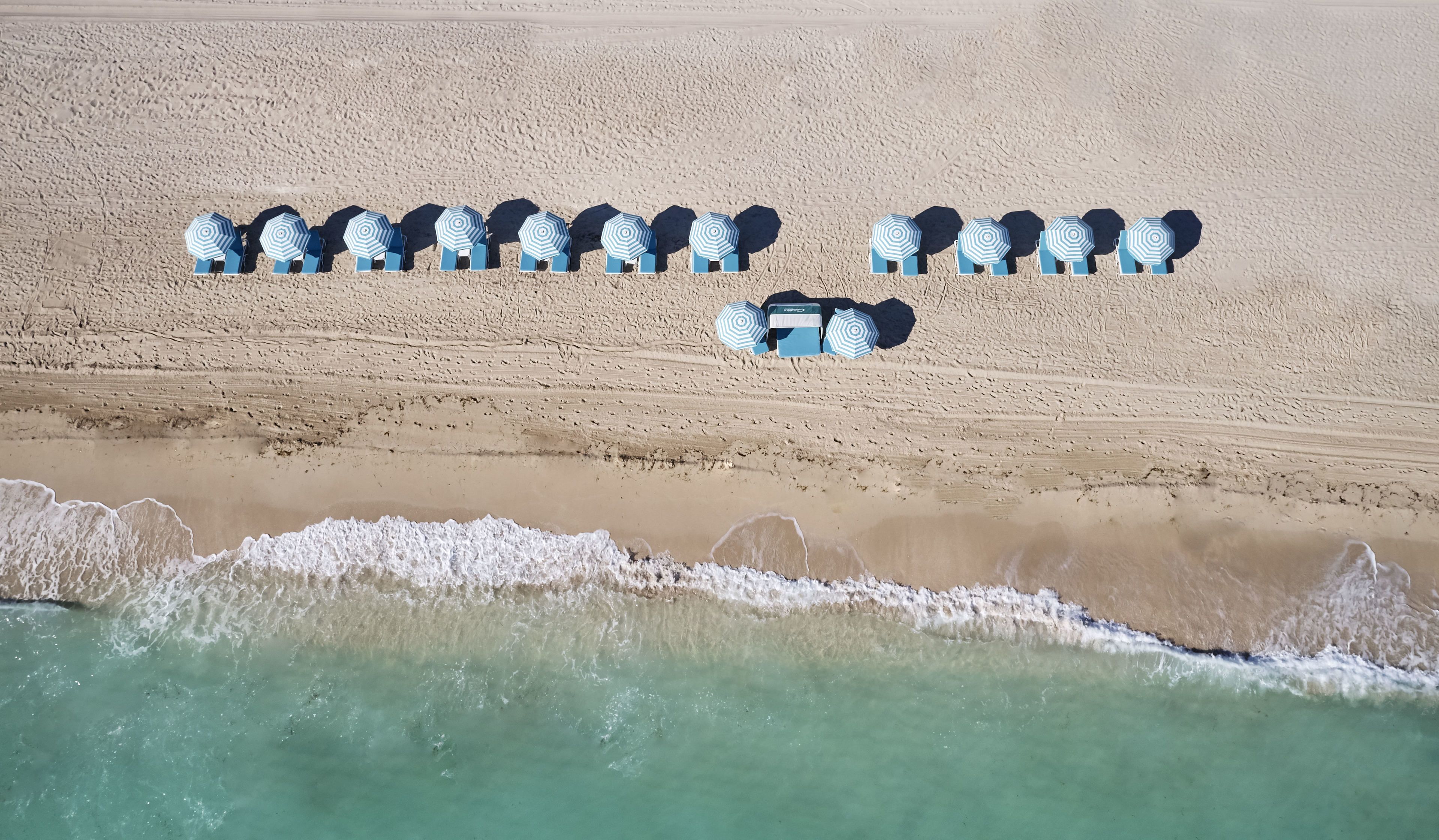 Na praia, areia branca, espreguiçadeiras, guarda-sóis 