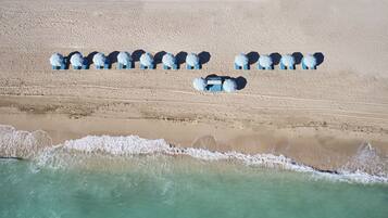 Na praia, areia branca, espreguiçadeiras, guarda-sóis