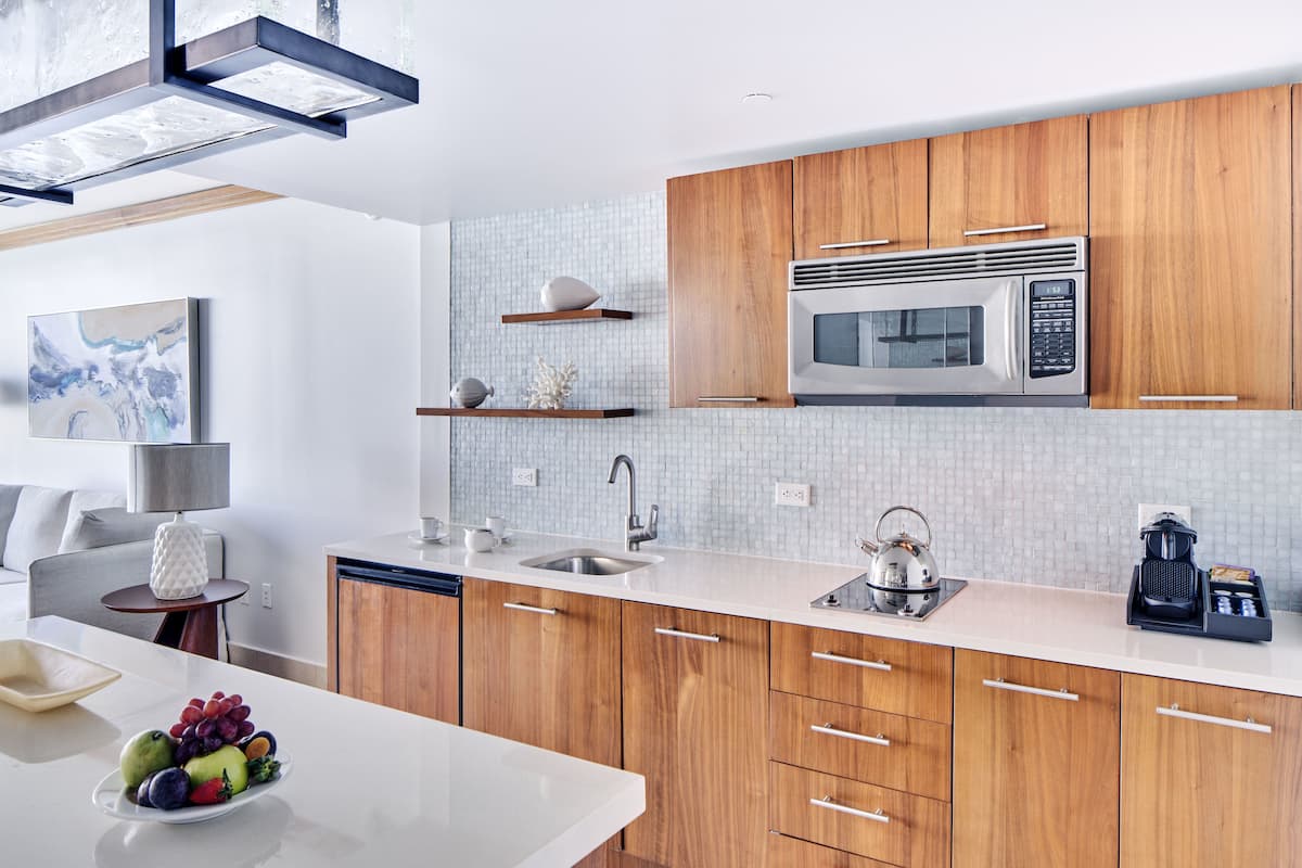 A modern kitchen with wooden cabinets, a stainless steel microwave, and a white countertop.