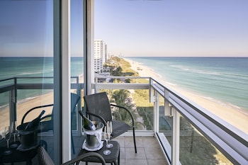 A modern hotel with a central courtyard featuring palm trees and a pathway leading to the beach. at Carillon Miami Wellness Resort