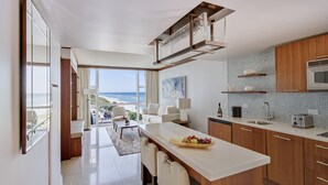 A modern kitchen with a large island, wooden cabinets, and a view of the ocean. - Carillon Miami Wellness Resort (Miami Beach)