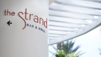 A wall sign for 'the Strand Bar & Grill' with an arrow pointing left.
