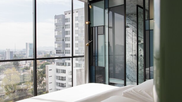 Une chambre moderne avec une grande fenêtre, un lit et un espace douche.