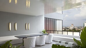 Un salon moderne avec une grande table, des canapés blancs et un balcon offrant une vue sur la ville.