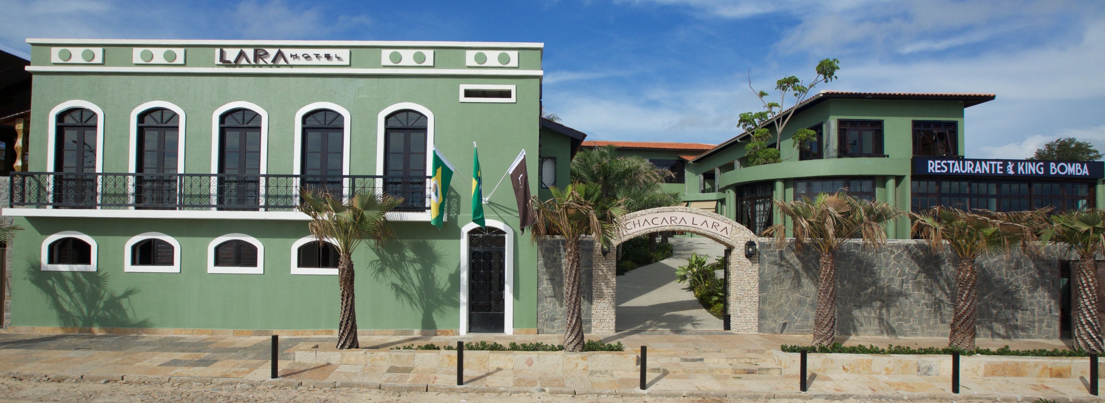 Um hotel chamado LARA com fachada verde, várias janelas em arco e entrada de pedra.
