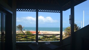 Una habitación con vista a la playa y al océano, a través de una ventana con celosía.