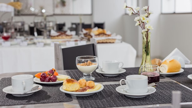 Una colazione con diversi cibi su piatti, tra cui frutta, pasticcini e un bicchiere di succo.