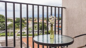 Un balcone con un tavolino in vetro e un vaso di fiori, con vista sulla città.