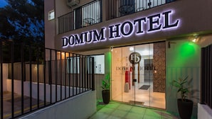 L'ingresso di un hotel con un cartello che riporta la scritta "DOMUM HOTEL" e una porta in vetro.