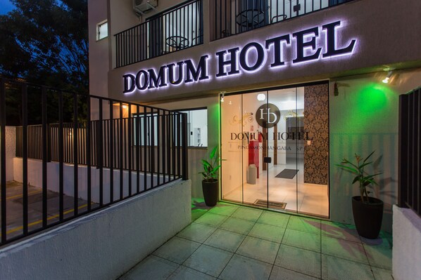 A hotel entrance with a sign reading "DOMUM HOTEL" and a glass door. - Domum Hotel (Pindamonhangaba)