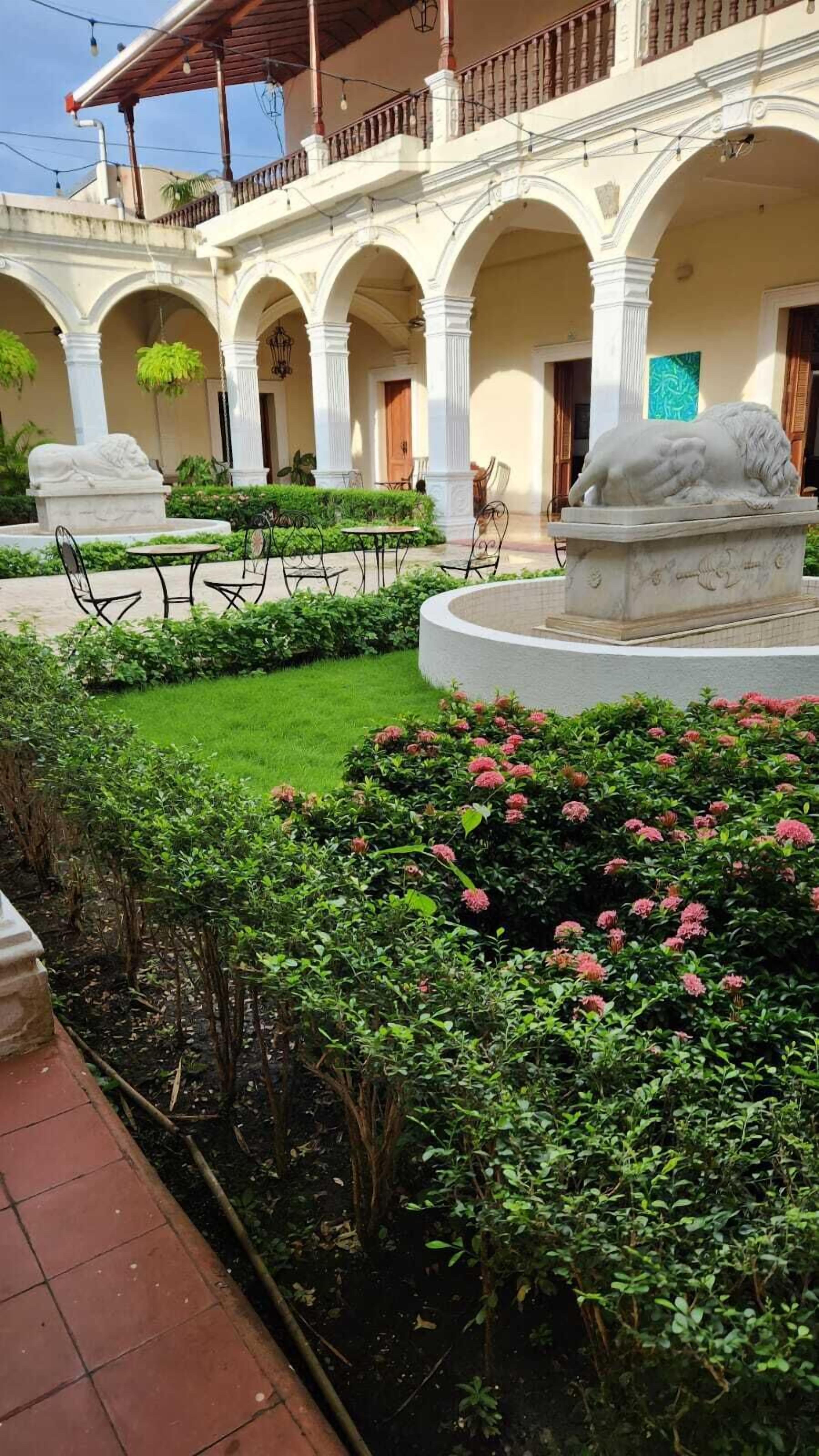 A courtyard with a fountain, seating area, and a building with arches and columns.