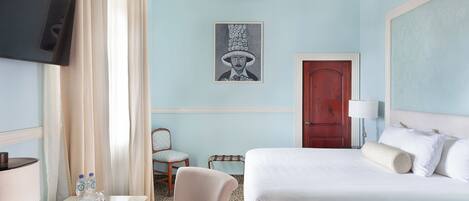 Una habitación de hotel con cama, escritorio, silla, televisor y puerta.
