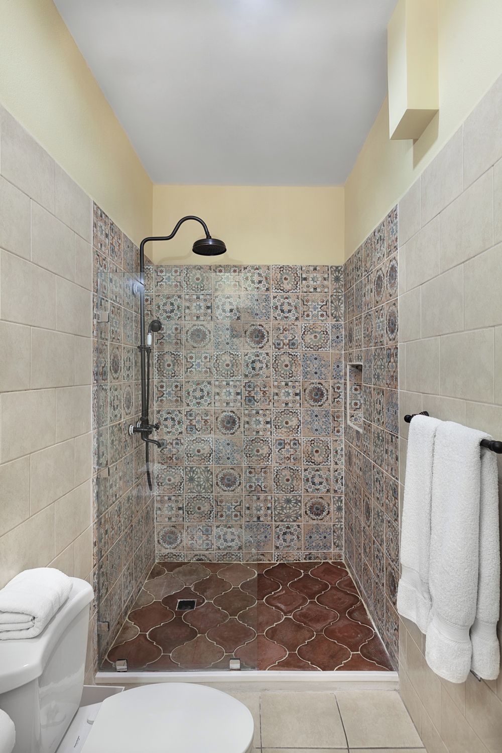 A bathroom with a shower, toilet, and a towel rack.