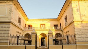 A hotel with a central courtyard, arched entrances, and a sign indicating it is a hotel. - Hotel La Perla (León)