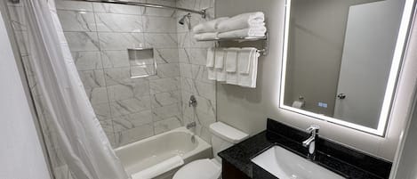 Een moderne badkamer met een bad, toilet en wastafel.