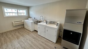 Cocina compacta con lavadora y secadora integradas, refrigerador de acero inoxidable y ventana que proporciona luz natural.