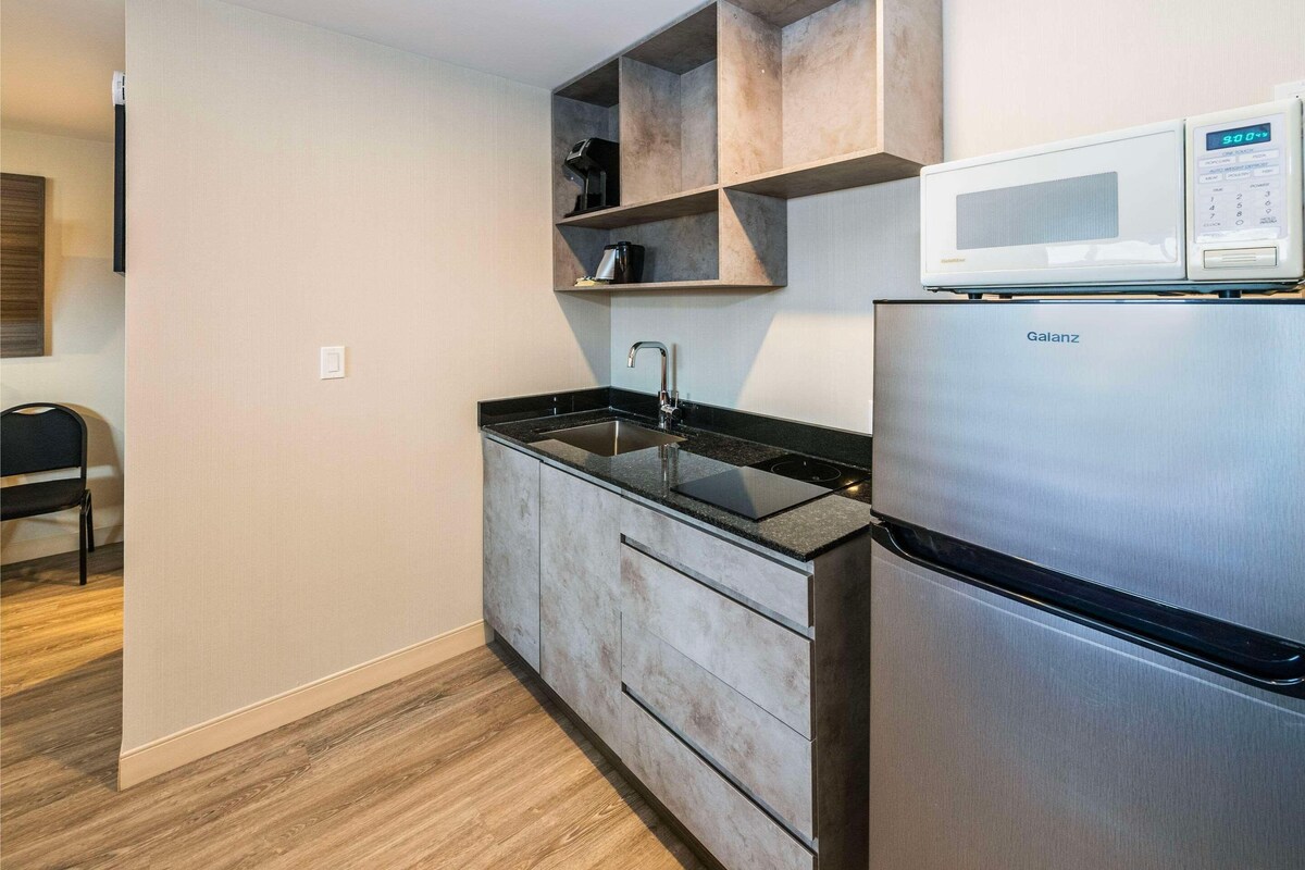 A modern kitchen with a built-in sink, a stainless steel refrigerator, and a microwave on top.