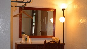Une petite salle de bain avec un meuble-lavabo en bois, un miroir, un porte-serviettes mural et un luminaire fixé au mur.