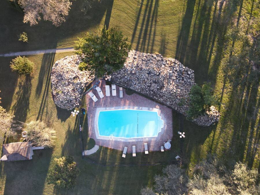 An aerial view of a property with a swimming pool, lounge chairs, and a stone patio.