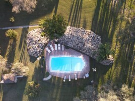 Vista aérea de una propiedad con piscina, sillas de descanso y un patio de piedra.