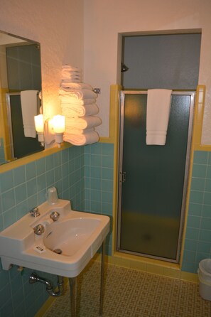 A bathroom with a sink, mirror, and a glass-enclosed shower.