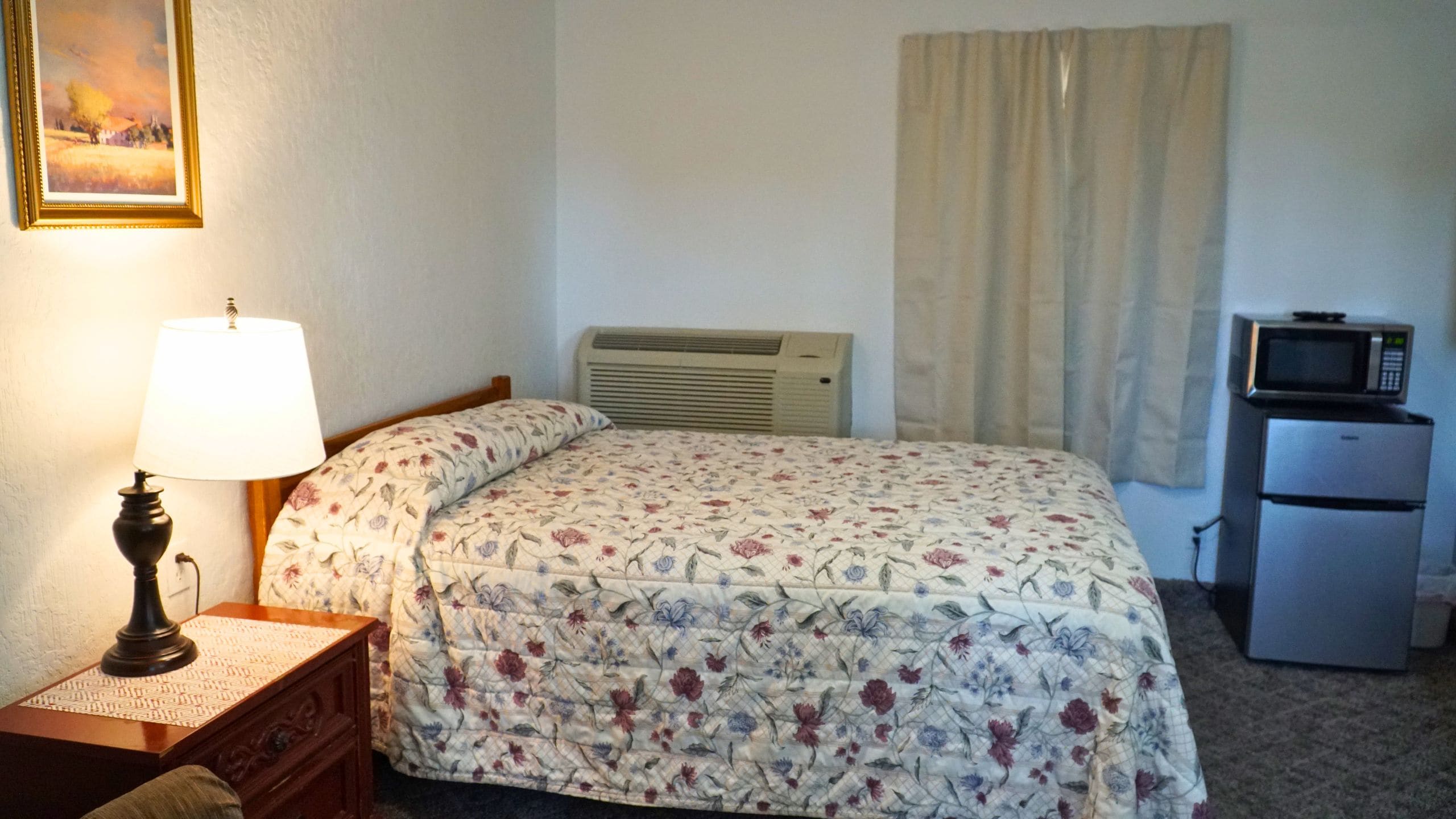 A room with a bed, a bedside lamp, a heater, a television, and a refrigerator.