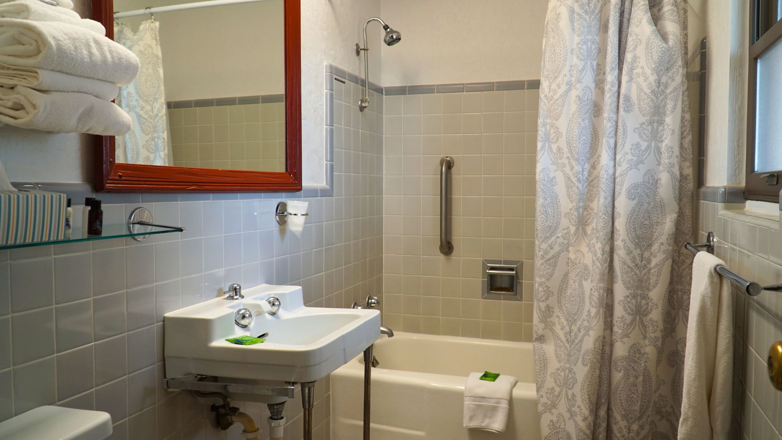 A bathroom with a sink, mirror, shower, and toilet.