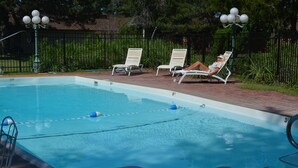 Une piscine avec des chaises longues et une clôture.