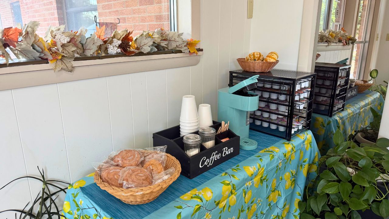 Comestibles d'un bar de cafeteria amb cistells de pa, una estació de cafè i fulles decoratives d'autunni.