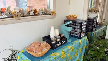 Una barra de café con cestas de pan, una estación de café y hojas otoñales decorativas.