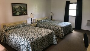 Une chambre d’hôtel avec deux lits, un tableau au mur, une fenêtre avec des rideaux et un radiateur.
