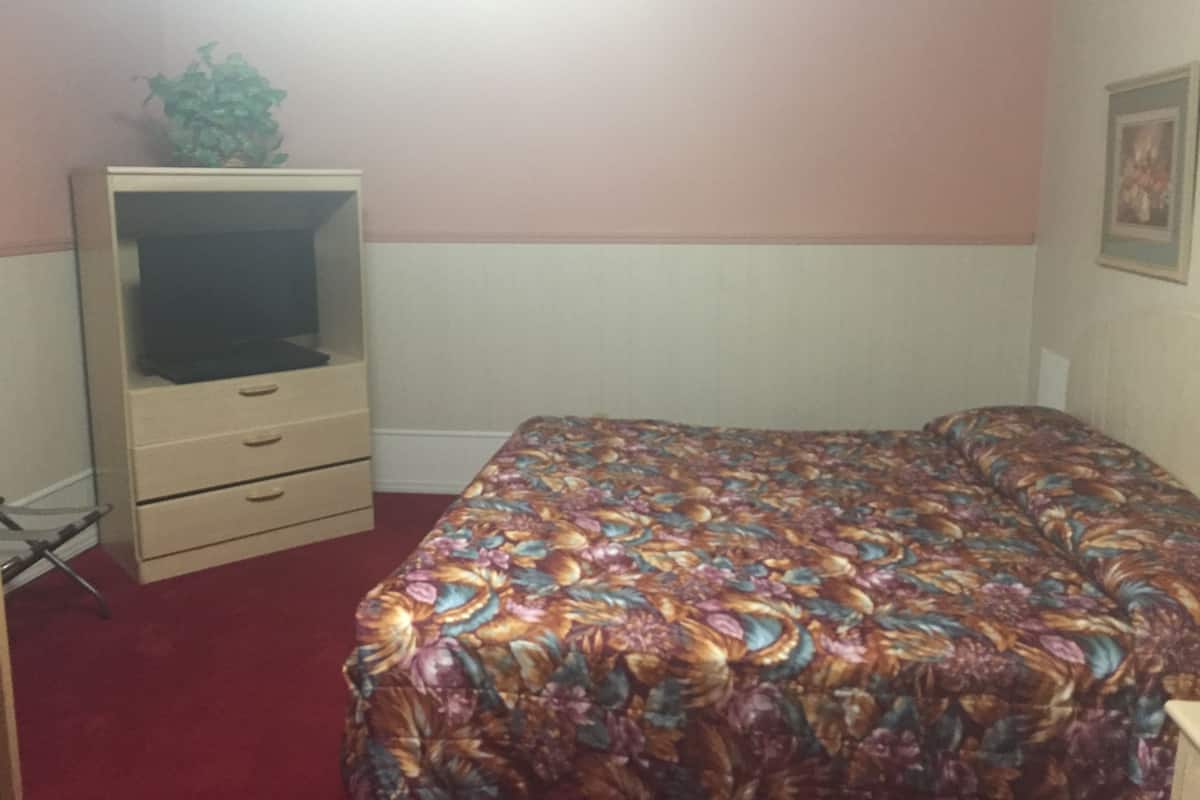 Un dormitorio con cama, cómoda y una planta.