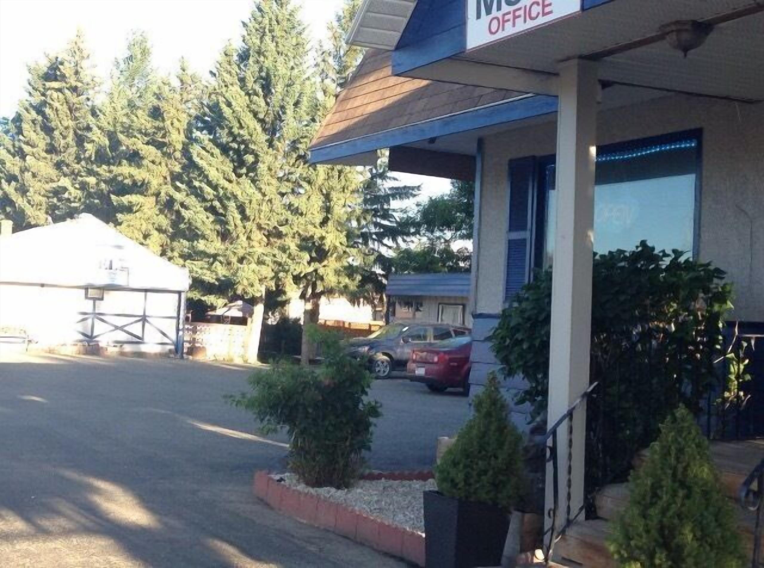 A building with a sign reading "OFFICE" and a covered entrance area with a car parked outside.
