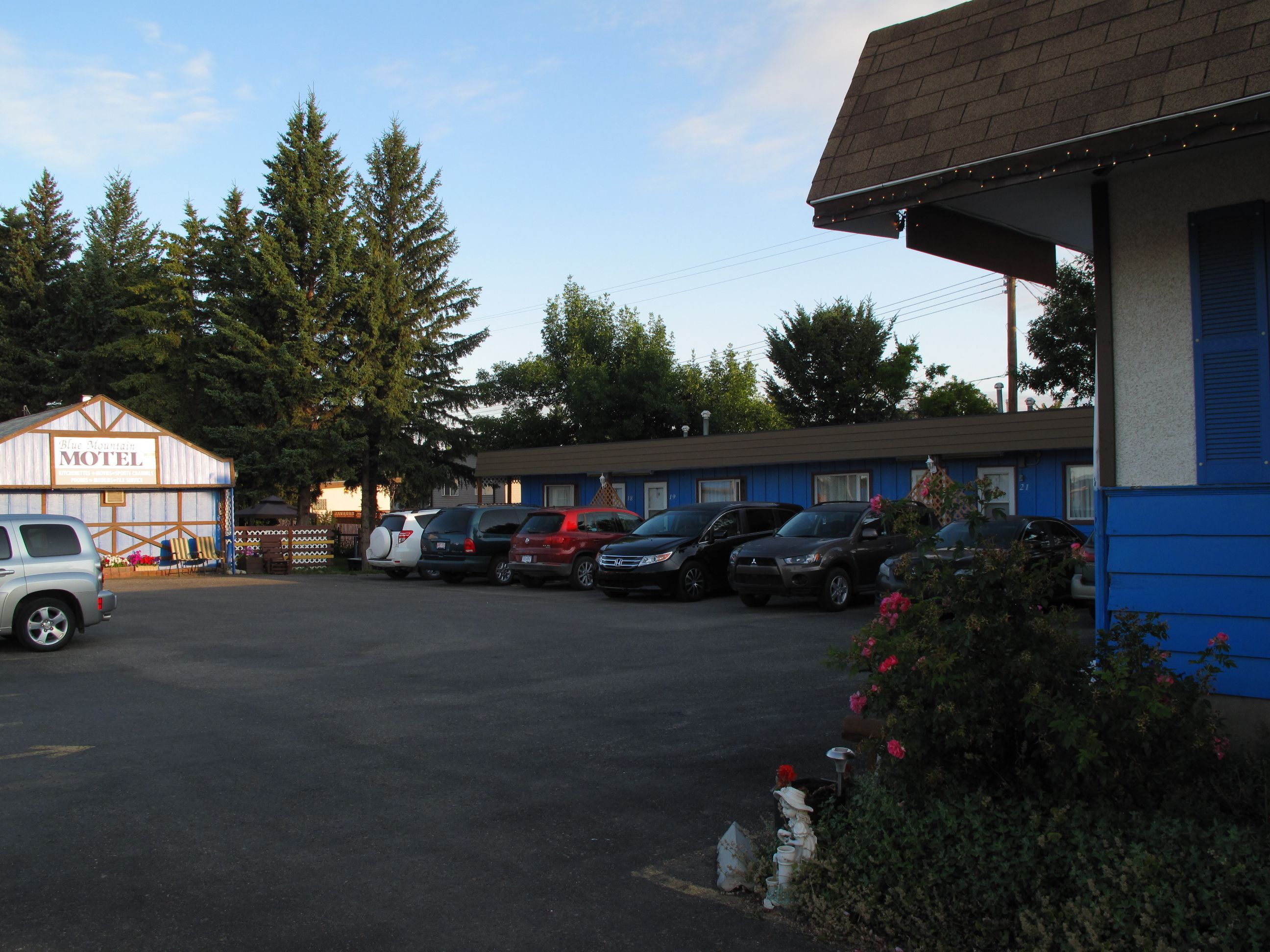A motel with a parking lot, several parked cars, and a building with a blue exterior.