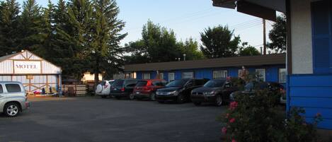 A motel with a parking lot, several parked cars, and a building with a blue exterior.