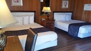 Ett hotellrum med två sängar, en byrå i trä, en lampa och en spegel.