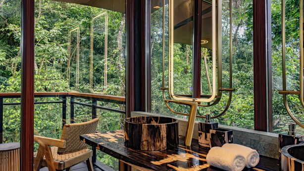 A modern bathroom with a large window, a wooden chair, a round wooden basin, and a towel rack. - Tifakara by the Waterfall (La Fortuna)