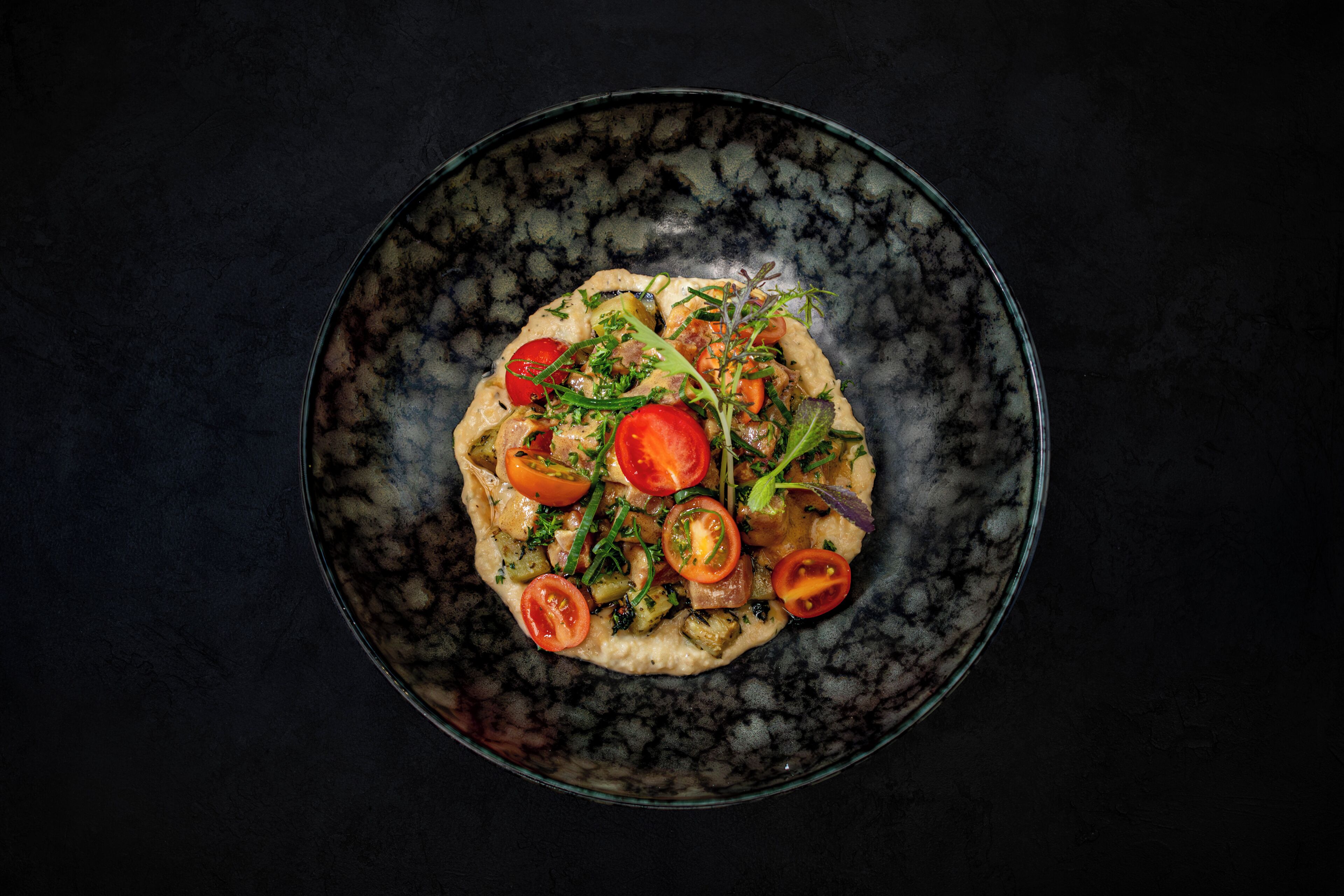 Un plato oscuro con verduras y tomates.