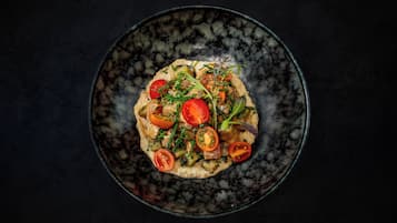Un plato oscuro con verduras y tomates.