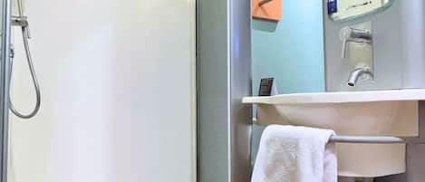 Un baño moderno con cabina de ducha de vidrio, un lavamanos con espejo y un perchero para toallas.