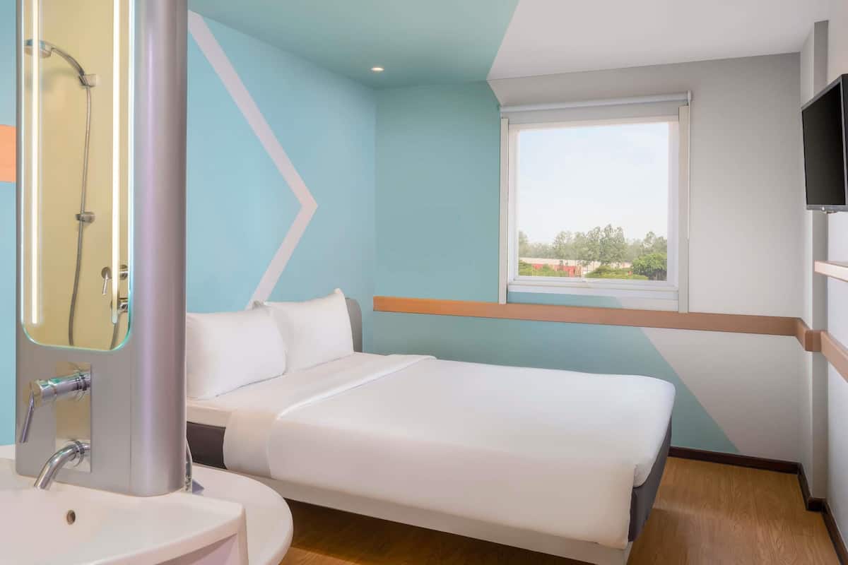 Ein Hotelzimmer mit Bett, Fenster mit Blick, Fernseher und Duschbereich.
