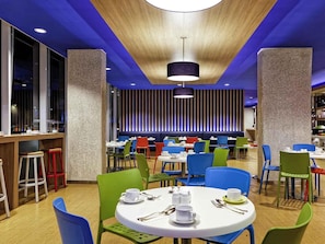 A modern dining area with round tables, colorful chairs, and a blue ceiling. - Hotel ibis budget Jakarta Airport (Tangerang)