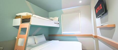 A room with a bunk bed, a television mounted on the wall, and a window.