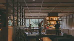 Een modern interieur met een eethoek, een bar en een zithoek met uitzicht op groen.