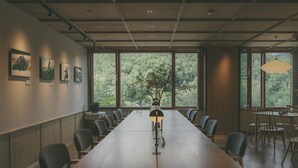 Een vergaderruimte met een lange tafel, stoelen en een potplant.
