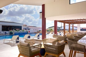 Zona de piscina en la azotea con mobiliario de mimbre y vistas de los edificios circundantes.